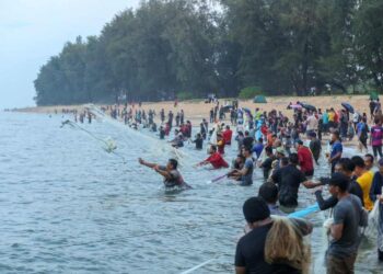 PENGUNJUNG dalam dan luar negeri bersama ahli keluarga masing-masing berpesta menjala sotong di pesisir pantai Seberang Marang, Marang, Terengganu. -UTUSAN/PUQTRA HAIRRY