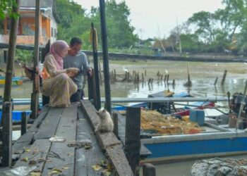 NUR Diana Zahirah Yusni,18, (kiri) menunjukkan keputusan cemerlang semua 9A SPM kepada bapanya di jeti nelayan, Kampung Sanglang, Arau, Perlis baru-baru ini.-UTUSAN/IZLIZAN OTHMAN