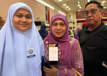 NUR  Syahirah  Syazwan  Zailani (kiri) menunjukkan keputusan SPM 2025 sambil diperhatikan kedua ibu bapanya di SMKA) Naim Lilbanat, Kota Bharu, Kelantan semalam- UTUSAN/ ROSLIZA MOHAMED