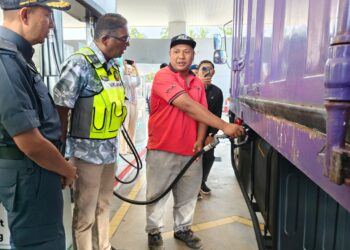 S. JEGAN (dua dari kiri) menyapa seorang pemandu yang sedang mengisi diesel ke dalam tangki lorinya di sebuah stesen minyak di Sungai Dua, Butterworth, Pulau Pinang.-UTUSAN/ISWAN SHAFIQ ISA