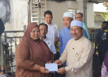 MOHD. Nassuruddin Daud (kanan) menyampaikan sumbangan kepada salah seorang mangsa kebakaran di Chabang Tiga Kedai Buluh, Kota Bharu, Kelantan hari ini-UTUSAN/YATIMIN ABDULLAH.