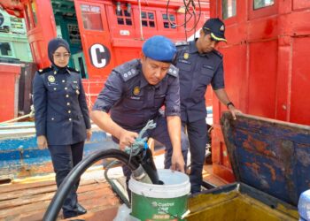 ASWADI Jaafar (tengah) bersama pegawai menunjukkan diesel seludup yang dirampas selepas menahan empat buah bot di jeti nelayan Kampung Geting, Tumpat, Kelantan-UTUSAN/ROHANA ISMAIL.