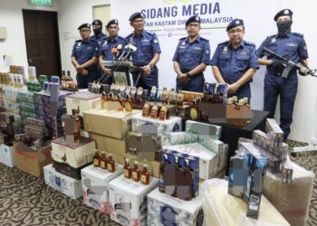 ROHAIZAD Ali (tengah) bersama sebahagian daripada rokok dan minuman keras tidak berkastam bernilai RM3.6 juta yang dirampas dalam satu serbuan di Bukit Mertajam, bulan lepas.-UTUSAN/DANIAL SAAD