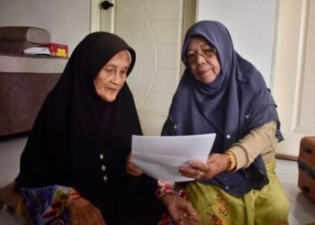 NORMA Ngah (kanan) dan Romlah Din (kiri) melihat surat tawaran menunaikan haji dan bakal berangkat ke tanah suci itu minggu depan di Kampung Sungai Padang, Arau, Perlis semalam. -UTUSAN/ASYRAF MUHAMMAD
