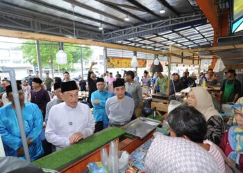 ANWAR Ibrahim (kiri) menyantuni orang ramai di Pasar Tani Kekal Permas Jaya, di Johor Bahru sebelum turut menunaikan solat Jumaat di Masjid Bandar Permas Jaya, di sini.
