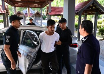 MUHAMMAD Firdaus Zamri diiringi anggota polis semasa dibawa ke Mahkamah Sesyen Kuala Terengganu.