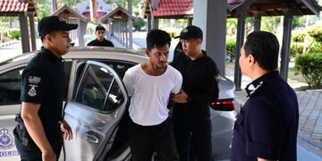 MUHAMMAD Firdaus Zamri diiringi anggota polis semasa dibawa ke Mahkamah Sesyen Kuala Terengganu.