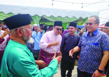 MAHFODZ Mohamed (kiri) menyambut ketibaan Ahmad Samsuri Mokhtar pada majlis Rumah Terbuka Aidilfitri Pas Negeri Johor di Bukit Pasir, Pagoh, Muar.