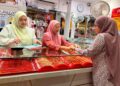 SEORANG pelanggan mencuba rantai tangan yang dijual di sebuah kedai emas di Pasar Siti Khadijah, Kota Bharu, Kelantan. – UTUSAN/ ROSLIZA MOHAMED