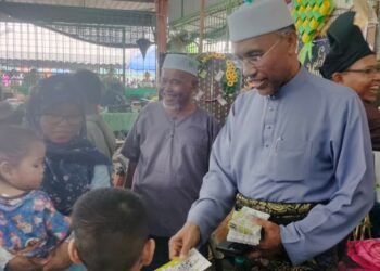 IDRIS Ahmad memberikan duit raya kepada kanak-kanak pada Rumah Terbuka Hari Raya Aidilfitri Pas Kawasan Bagan Serai hari ini. - UTUSAN/WAT KAMAL ABAS