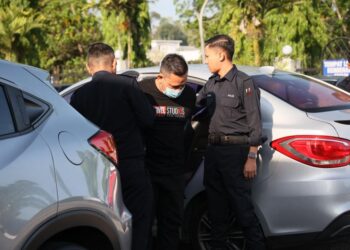 TERTUDUH diiringi anggota polis semasa menghadiri prosiding perbicaraan di Mahkamah Majistret Kuala Krai, Kelantan. - UTUSAN/KAMARUL BISMI KAMARUZAMAN