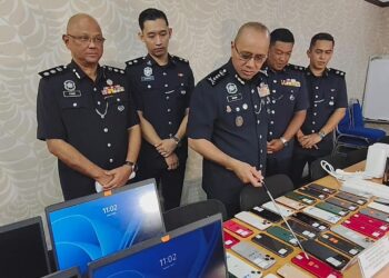 NOOR Hisam Nordin (tengah) menunjukkan rampasan yang dibuat dalam serbuan di sebuah inap desa di Bagan Datuk yang dijadikan sebagai pusat panggilan operasi pelaburan mata wang kripto tidak wujud.