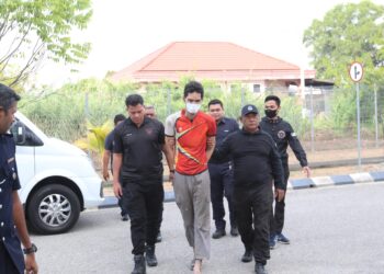 TERTUDUH diiringi polis semasa menghadiri prosiding perbicaraan di Mahkamah Majistret Kota Bharu, Kelantan. - UTUSAN/KAMARUL BISMI KAMARUZAMAN
