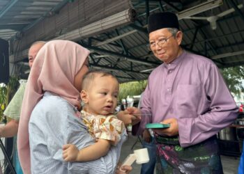MOHAMMAD Nizar Jamaluddin  memberi duit raya kepada pengunjung pada majlis Aidilfitri anjuran beliau di Ipoh hari ini. - UTUSAN/LIYANA RAMLI