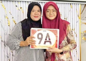 NURUL Aisyah Sahidrasul (kanan) mengabadikan gambar kenangan bersama ibunya selepas mengambil keputusan SPM 
di SMK Kinabutan II, Tawau. – UTUSAN