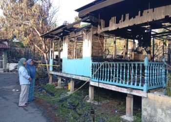 NORHASLINA Awang (kiri) melihat keadaan rumah pusaka yang didiaminya musnah dalam kebakaran di Kampung Buluh Gading,Kuala Terengganu,Terengganu.- UTUSAN / ERMA YUSNIDA JUSOH
