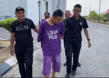 TERTUDUH (tengah) diiringi polis semasa menghadiri prosiding perbicaraan di Mahkamah Kota Bharu, Kelantan.