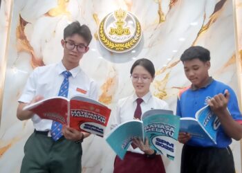 (Dari kanan) ASRI Alangka, Monessa Loo Wing Kaa dan Lam Ming Hin melihat buku rujukan tambahan SPM yang mereka terima di bawah Program Tuisyen Cikgu Saarani di Ipoh. - UTUSAN/MEGAT LUTFI MEGAT RAHIM