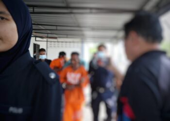 SUSPEK diiringi polis semasa menghadiri prosiding reman di Mahkamah Majistret Tanah Merah, Kelantan. - UTUSAN/KAMARUL BISMI KAMARUZAMAN