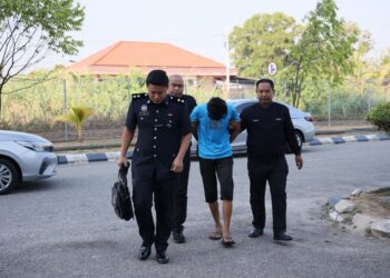 TERTUDUH diiringi polis semasa menghadiri prosiding perbicaraan di Mahkamah Kota Bharu, Kelantan. I- UTUSAN/KAMARUL BISMI KAMARUZAMAN.