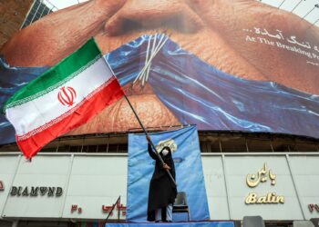 PIX 2 - SEORANG wanita mengibarkan bendera Iran di hadapan papan iklan anti-AS di Dataran Valiasr, Teheran kelmarin.- AFP