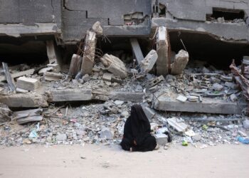 SEORANG wanita duduk di depan runtuhan di Khan Yunis, Gaza, Selasa lalu. - AFP