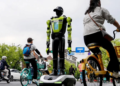 ORANG ramai berbasikal melepasi pegawai polis robot humanoid di Hangzhou di wilayah Zhejiang, China.-AFP