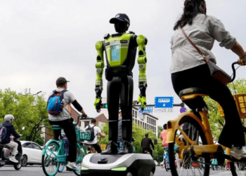 ORANG ramai berbasikal melepasi pegawai polis robot humanoid di Hangzhou di wilayah Zhejiang, China.-AFP