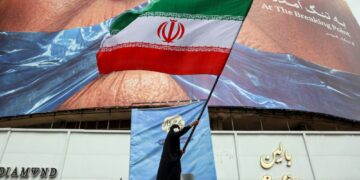 SEORANG wanita mengibarkan bendera Iran di hadapan papan iklan anti-Amerika yang merujuk kepada Presiden Donald Trump dan Selat Hormuz di Dataran Valiasr di Teheran.- AFP