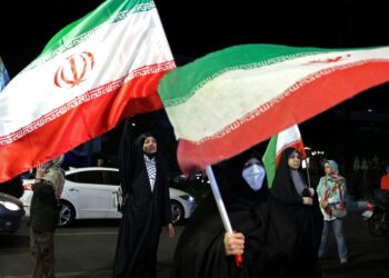 WANITA memegang bendera kebangsaan Iran semasa protes anti-AS dan Israel di Dataran Hafte Tir di Teheran.- AFP