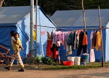 SEORANG wanita mendukung kanak-kanak melalui khemah-khemah di pusat pemindahan di wilayah Banteay Meanchey, ekoran pertempuran sempadan antara tentera Thailand dan Kemboja.- AFP