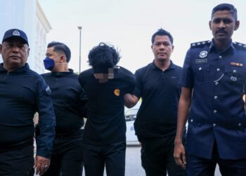 TERTUDUH diiringi polis semasa menghadiri prosiding pertuduhan di Mahkamah Kota Bharu, Kelantan hari ini. - UTUSAN/KAMARUL BISMI KAMARUZAMAN