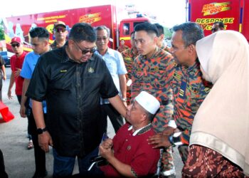 AB. Rauf Yusoh menyantuni salah seorang bekas anggota bomba yang berkerusi roda pada majlis meraikan Pesara Bomba dan Anggota Balai Bomba dan Penyelamat Parlimen Masjid Tanah hari ini. UTUSAN/AMRAN MULUP