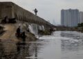 SEORANG lelaki dengan joran pancingnya berjalan di atas sebuah tembok laut yang dibina untuk menghalang air laut daripada membanjiri pesisir utara di Muara Baru, Jakarta.- AFP