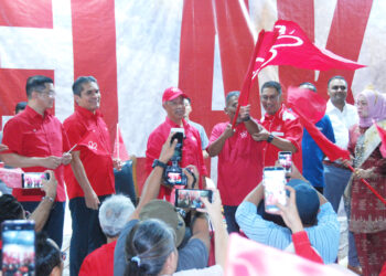 MUHYIDDIN Yassin menyerahkan bendera Bersatu kepada wakil setiap bahagian pada Majlis Pelancaran Jentera Pilihan Raya Bersatu di Dataran Baitul Tariq, Klebang Besar, Melaka malam tadi. UTUSAN/AMRAN MULUP