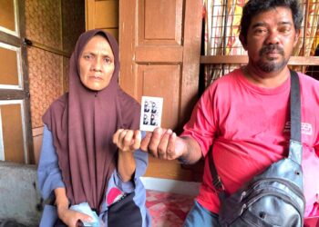 MOHD. Hamdan Jemaei dan Norfaziah Sahat menunjukkan gambar anak mereka yang maut dalam kemalangan jalan raya di Jalan Teluk Intan-Sitiawan pada Khamis lalu. - UTUSAN/AIN SAFRE BIDIN