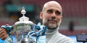 Pep Guardiola memegang Piala FA selepas pasukan bimbingannya menewaskan Chelsea 1-0 pada perlawanan akhir di Stadium Wembley, London, kelmarin. - AFP   