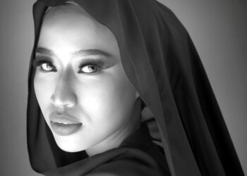 Merujuk kepada karya Muhammad Yusri Hakim Isharudin, pendedahan cahaya yang penuh perhitungan ini bukan sahaja mengekalkan tekstur halus pada kulit, malah ia bertindak sebagai instrumen emosi yang kuat. Jurugambar dengan bijak mengekploitasi julat tona daripada Zon VI pada wajah subjek yang bercahaya, sehinggalah ke tona gelap yang dalam pada lipatan hijab.
