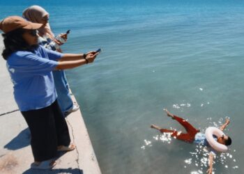 SEORANG pengunjung di Pantai Telok Kemang bersantai menikmati kejernihan pantai tersebut baru-baru ini. UTUSAN/MOHD. SHAHJEHAN MAAMIN