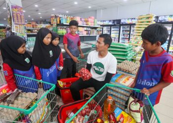 MAT Saidi Yusof (tengah) bersama sebahagian murid SK Bukit Jejulong, Marang, Terengganu membeli barangan asas keperluan rumah daripada duit hasil sumbangan orang ramai di sebuah pasar raya. – UTUSAN/PUQTRA HAIRRY