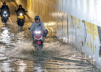 PENUNGGANG motosikal meredah laluan yang digenangi air selepas hujan akibat kelemahan sistem perparitan di Lebuhraya Persekutuan, Petaling Jaya, Selangor. –  UTUSAN/FARIZ RUSADIO