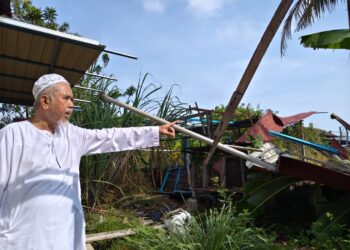 MUHAMAD Roslan Abd. Rahim menunjukkan bumbung garaj rumahnya yang diterbangkan ribut sejauh kira-kira 15 meter sehingga ke belakang rumah di Permatang Bertam, Kepala Batas, Pulau Pinang.-UTUSAN/ISWAN SHAFIQ ISA