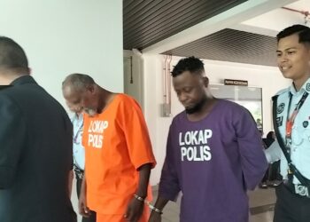 SUSPEK (baju ungu) dikawal ketat polis selepas permohonan reman di Mahkamah Sesyen, Alor Gajah, Melaka hari ini.