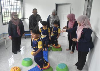 Mohamad Zaki Ismail (dua dari kiri) bersama guru-guru melihat anak-anak autisme melakukan aktiviti disediakan.