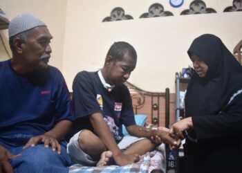 AZIZAN Saad (kiri) melihat Ummi Kalsom (kanan) menguruskan Muhammad Amirul Naim yang menderita sakit buah pinggang di Kampung Tebuk, Tambun Tulang, Arau, Perlis semalam. – UTUSAN/ASYRAF MUHAMMAD