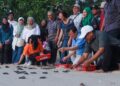 CHOW Kon Yeow (duduk, dua dari kanan) ketika menghadiri program pelepasan anak penyu sempena Jelajah CM Chow di Pantai Keracut, Teluk Bahang, Pulau Pinang, hari ini.-UTUSAN/DANIAL SAAD