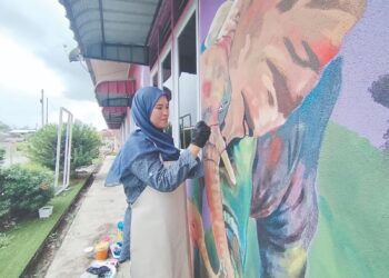 LIYA Najwa Lukman menyiapkan mural di dinding sebuah taman asuhan kanak-kanak di Kampung Pak Kancil, Setiu, Terengganu. - UTUSAN / WAN ZURATIKAH IFFAH WAN ZULKIFLI