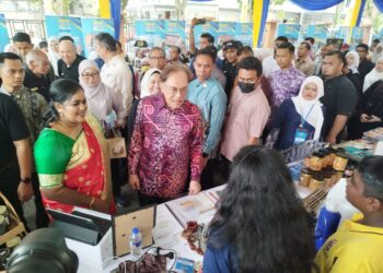 ANWAR Ibrahim (tengah) berbual dengan peniaga yang menyertai majlis peluncuran Skim Paduri Madani AIM di Ipoh, Perak hari ini.-FADZIL ZAINOL