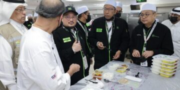 MUSTAKIM Mohamad (tengah) melihat pek sajian makanan yang direka khas ketika meninjau operasi dapur haji 2026/1447H di Mekah, semalam.