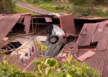 KEADAAN sebuah kereta yang hilang kawalan terjunam ke bumbung sebuah rumah di kaki bukit dekat Jalan Kampung Tanjung Bachang, Seri Menanti, Kuala Pilah, semalami. -GAMBAR / IHSAN POLIS